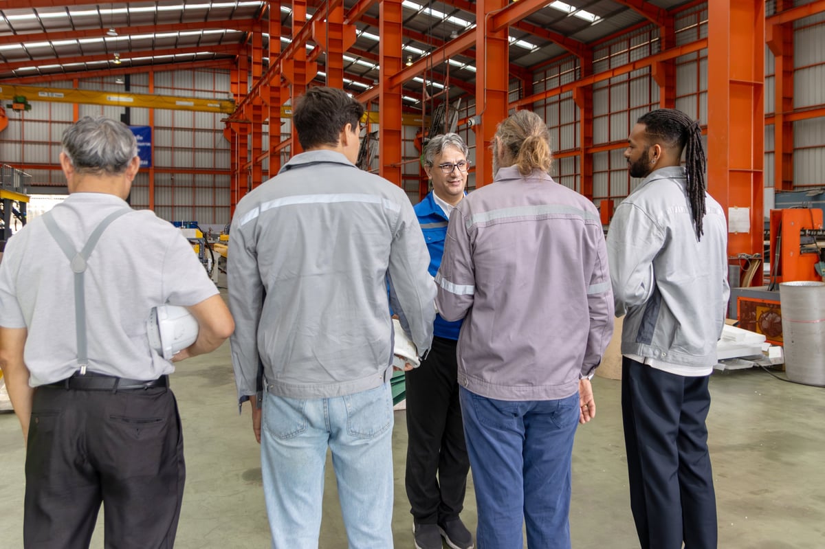 Supervisor briefing diverse team before working in manufacturing facility