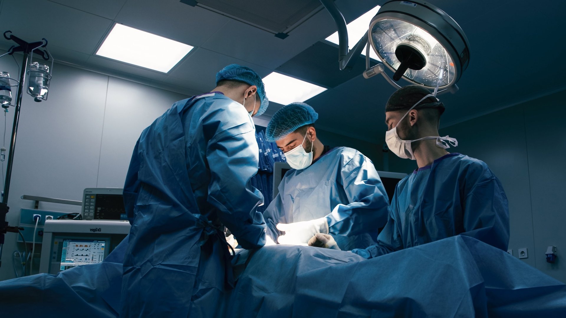 Equipo médico en cirugía con vestimenta quirúrgica azul trabajando en quirófano moderno