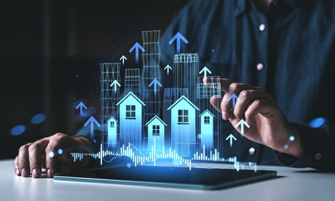 Hands interacting with tablet displaying digital houses, charts, and arrows