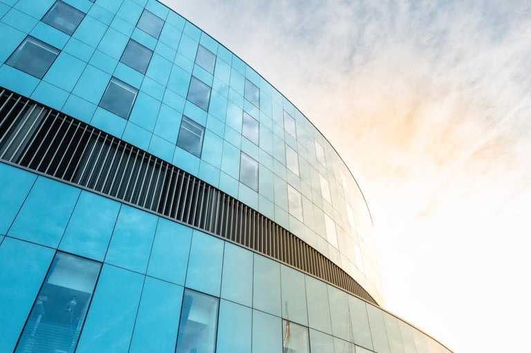Fachada moderna de hospital con diseño arquitectónico curvo, paneles de vidrio azul y luz natural — fotografía editorial premium