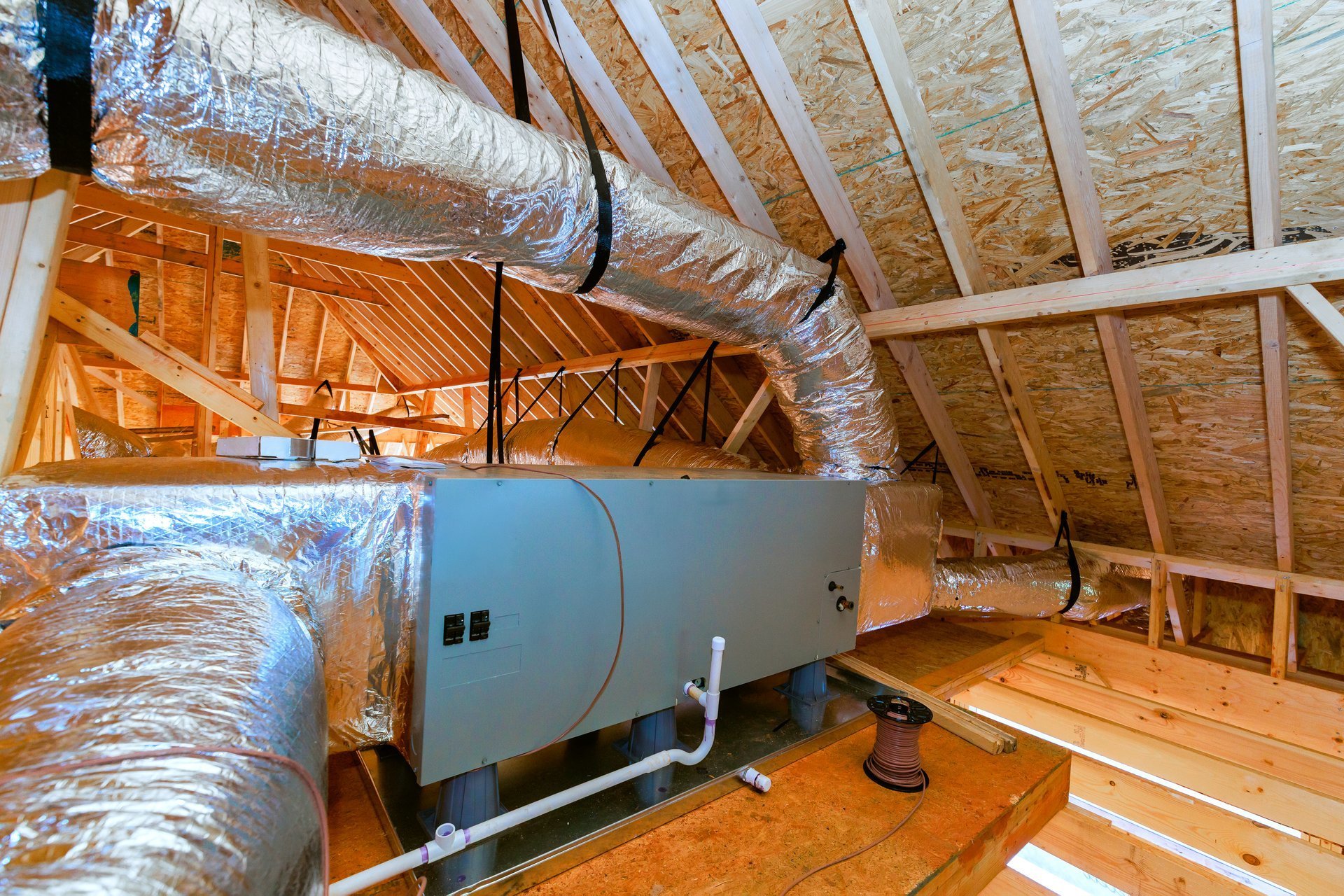 Workers installing a heating and cooling system in the attic of a home