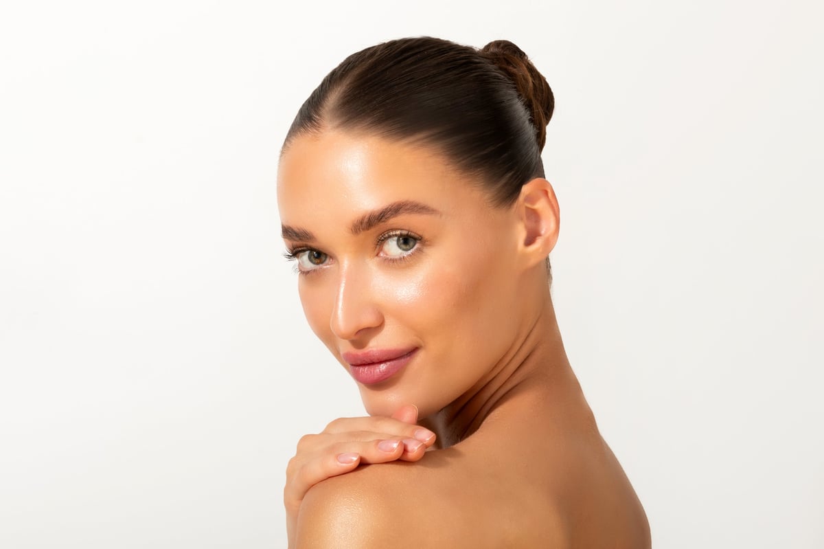 Portrait of elegant young woman with smooth, clear face skin, posing against white studio background
