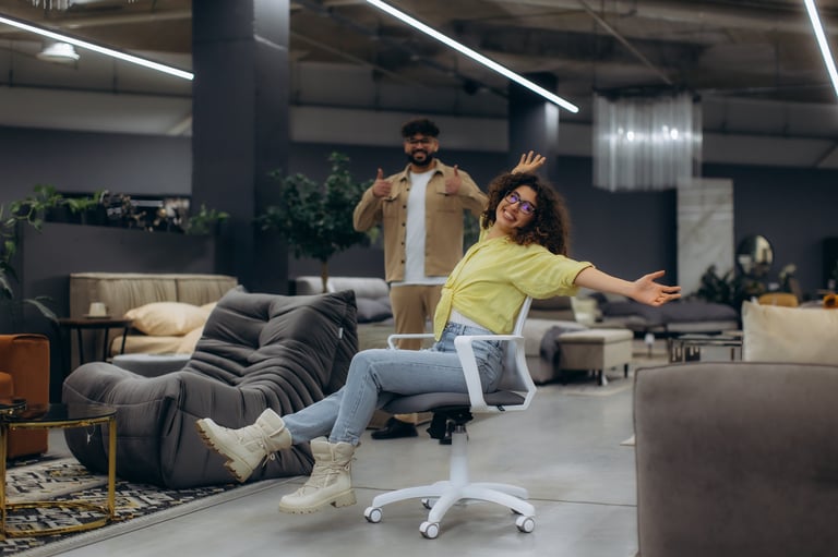 Happy customers at Furniture Haus Co Clearwater — woman trying a chair while man gives thumbs up in showroom