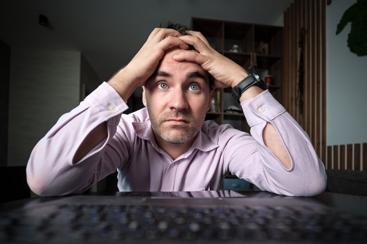 Person looking frustrated at a laptop screen while interacting with a website