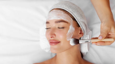 Aplicación de mascarilla facial con brocha en cabina de spa