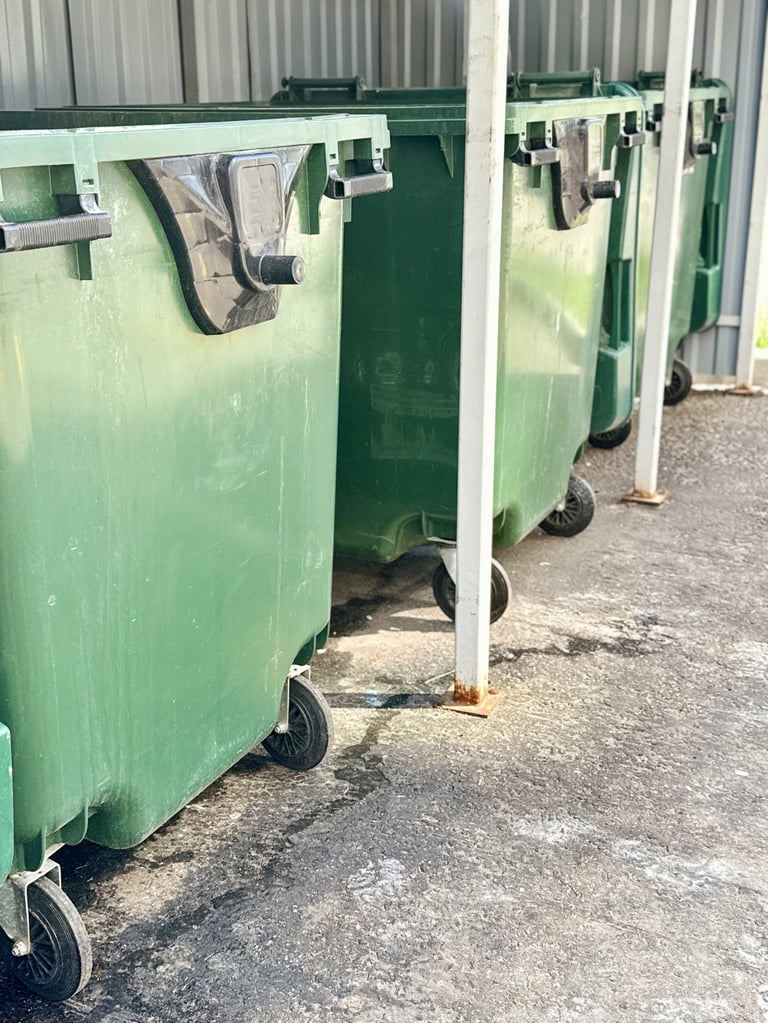 Green dumpsters lined against wall