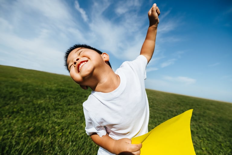 A joyful child running through a wide grassy field on a sunny day