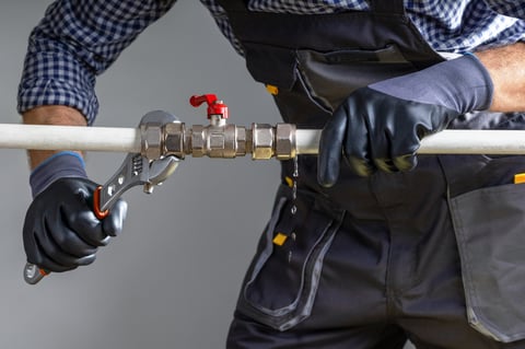 Plumber using a wrench to repair a water pipe