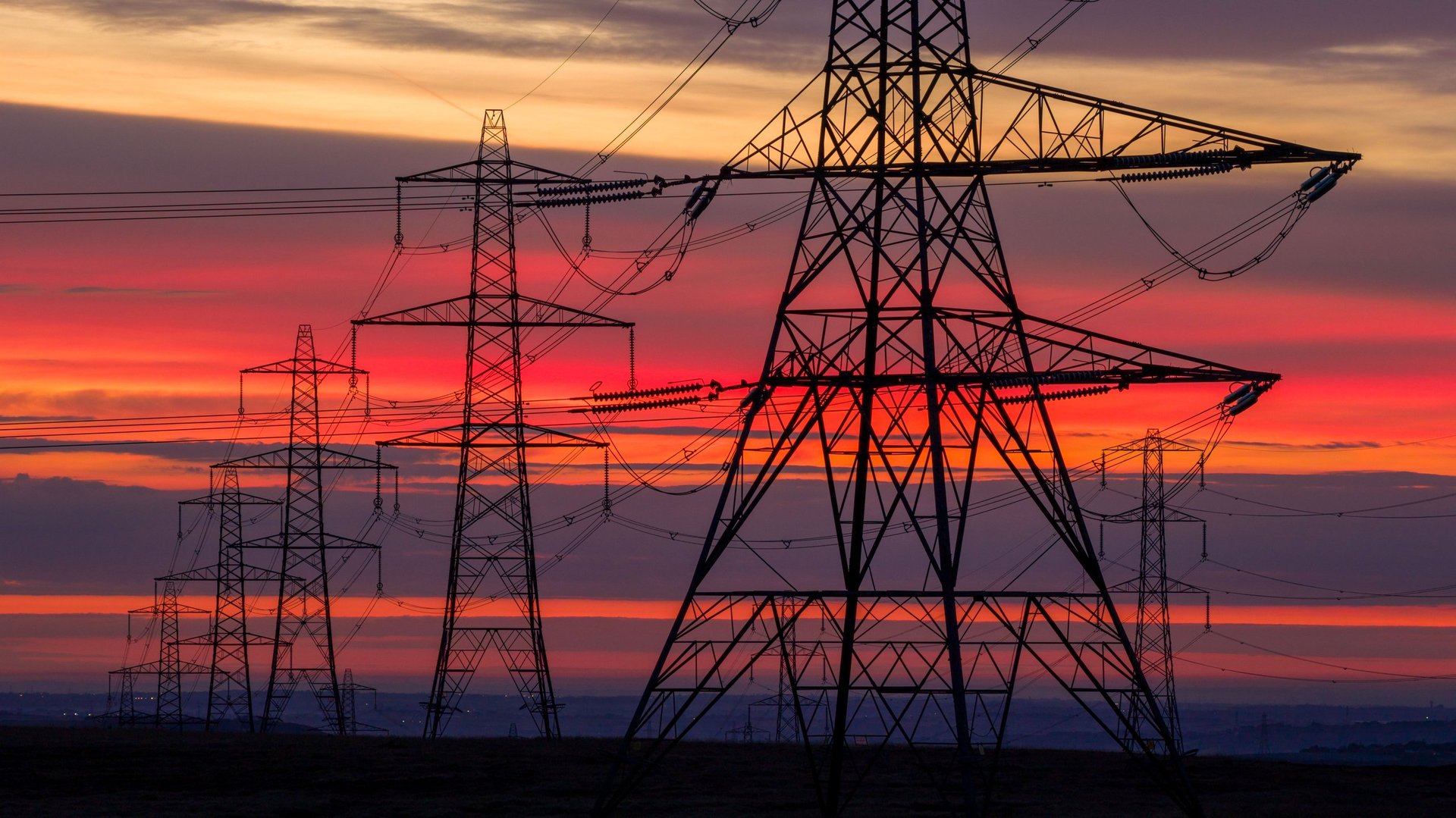 Electricity pylons and power infrastructure at sunset, modern energy grid