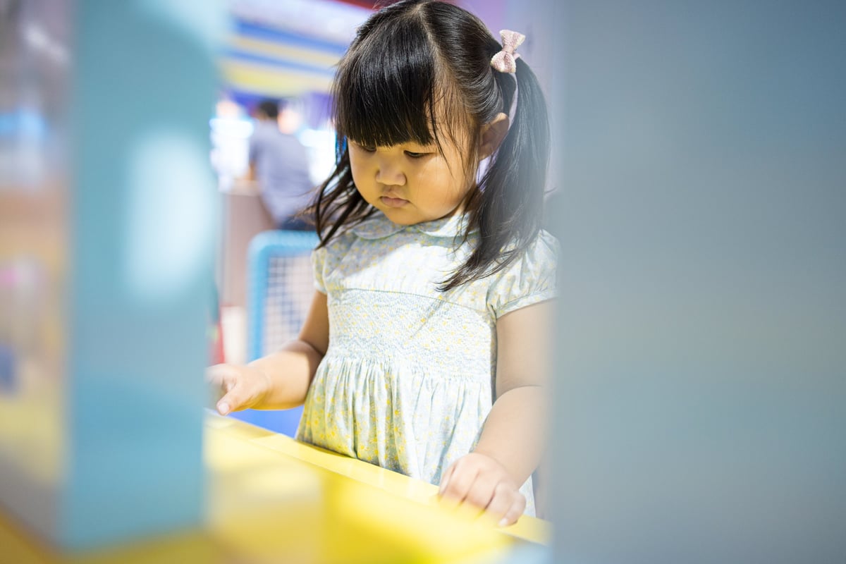 Little girl focusing while playing with colorful toys at a modern indoor playground