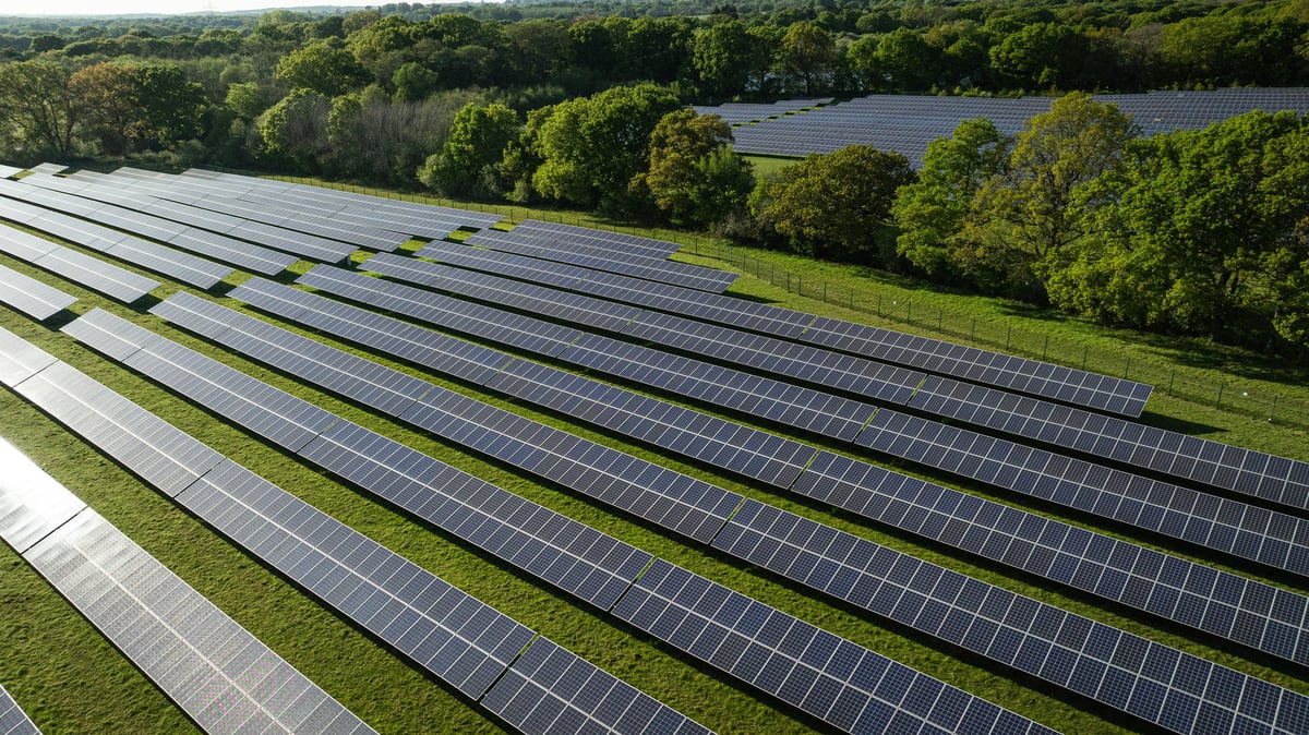 Aerial view of a solar farm set within green countryside and a lake