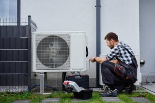 HVAC technician servicing outdoor heat pump unit