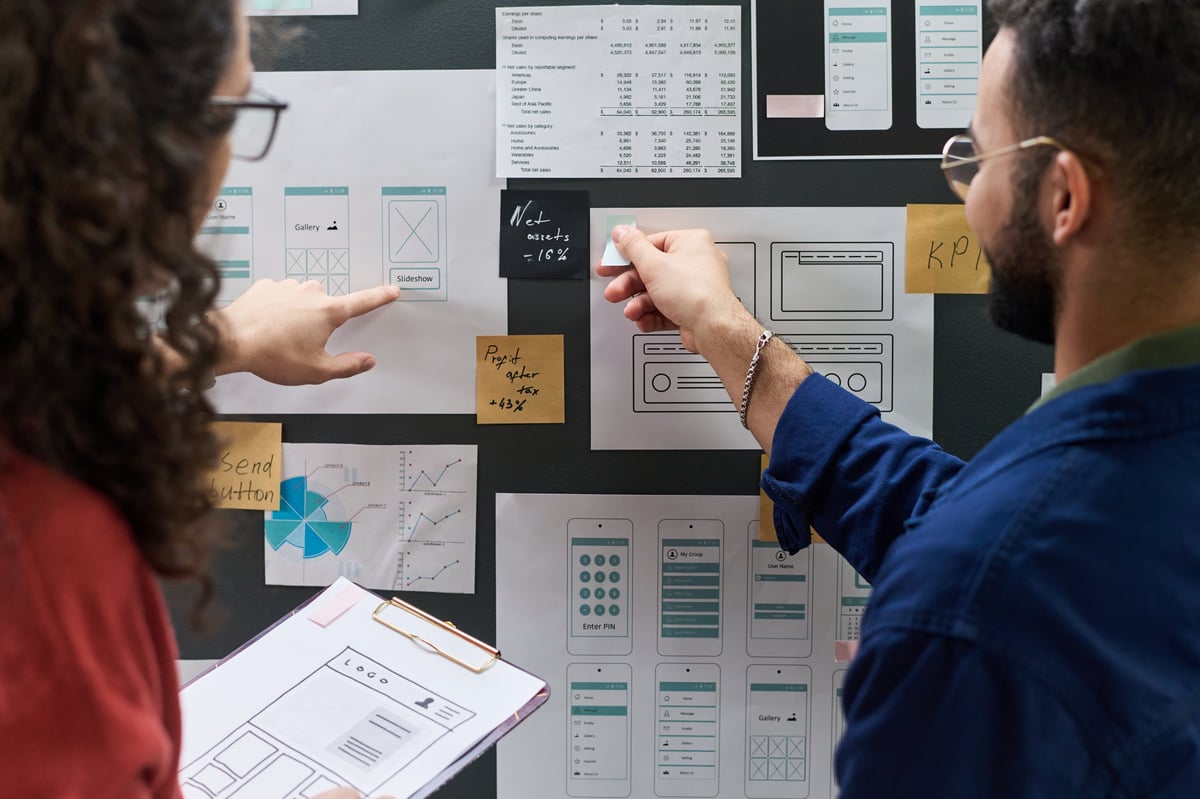 Two colleagues reviewing website wireframes and data charts during a redesign planning session
