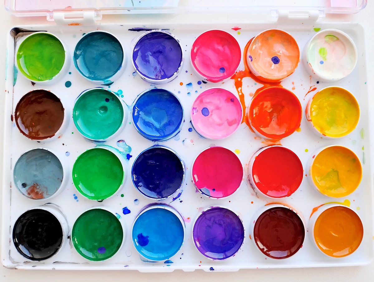 A designer's workspace with colour swatches, palette samples, and branding materials spread across a desk, illustrating the process of selecting brand colours
