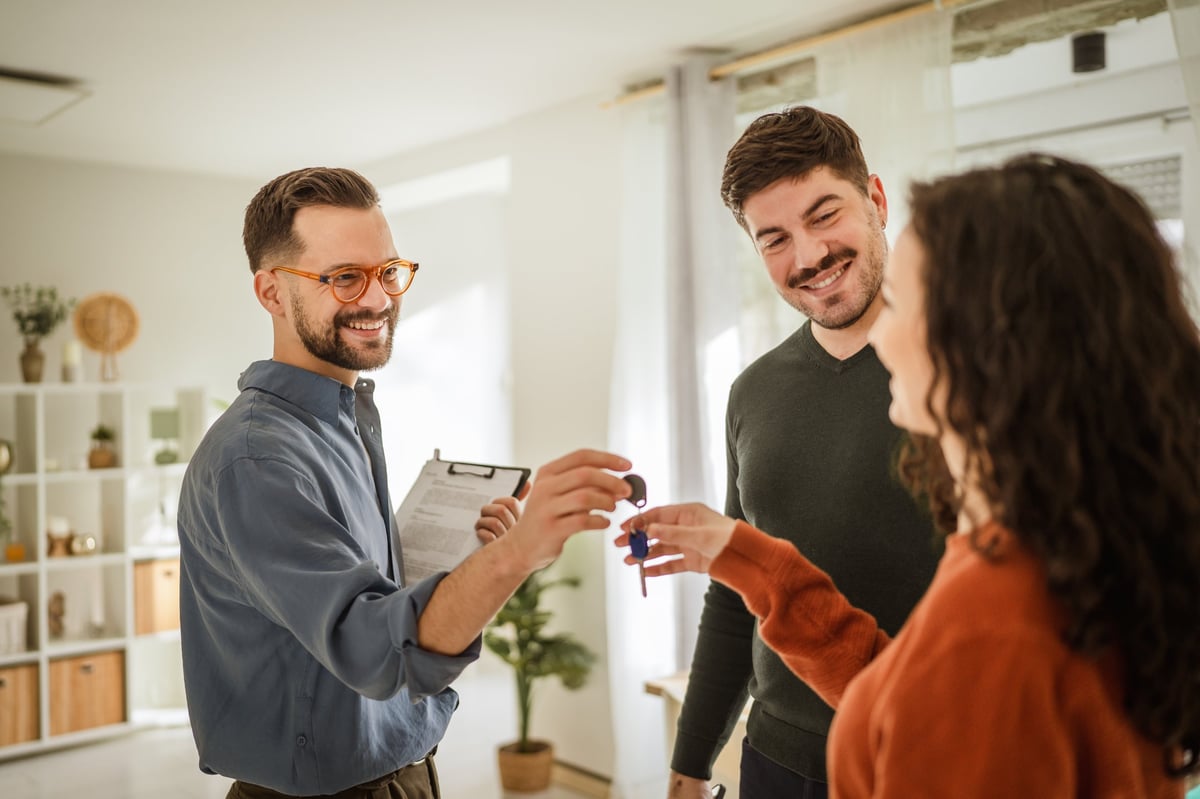 A professional handing keys to an adult entering an independent housing arrangement