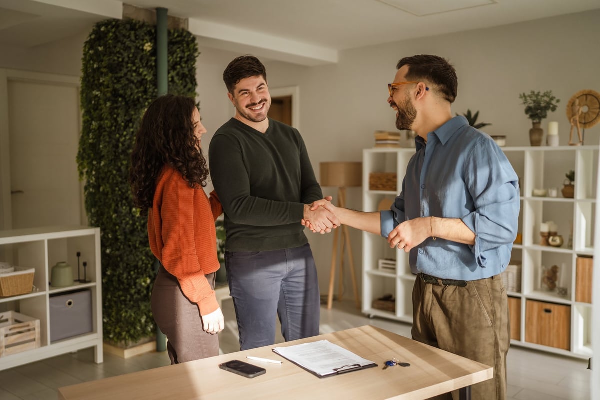 A case manager and an adult shaking hands, exchanging keys after a housing arrangement
