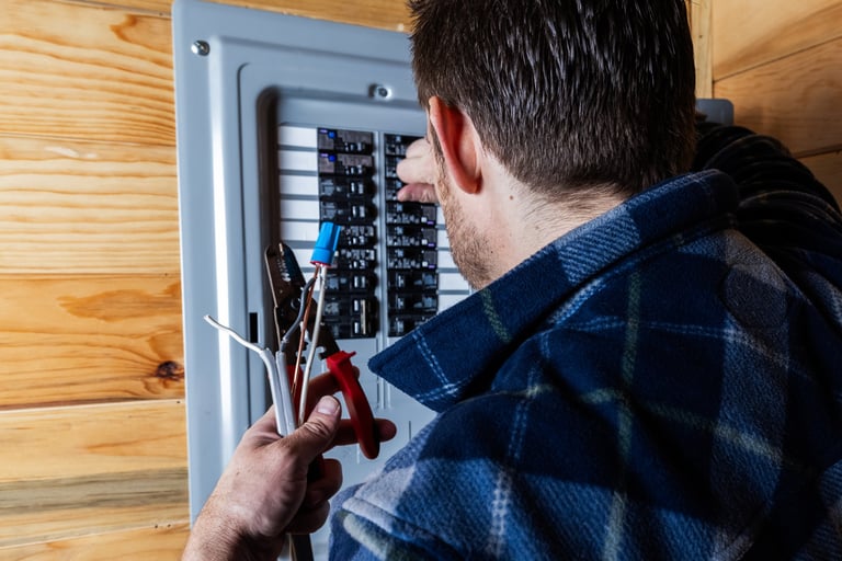 Electrician using wire strippers to prepare electrical cables in a residential circuit breaker panel