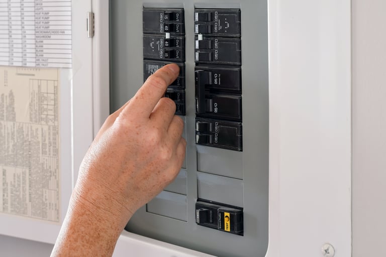 Woman's hand operating a residential electrical panel inside a home