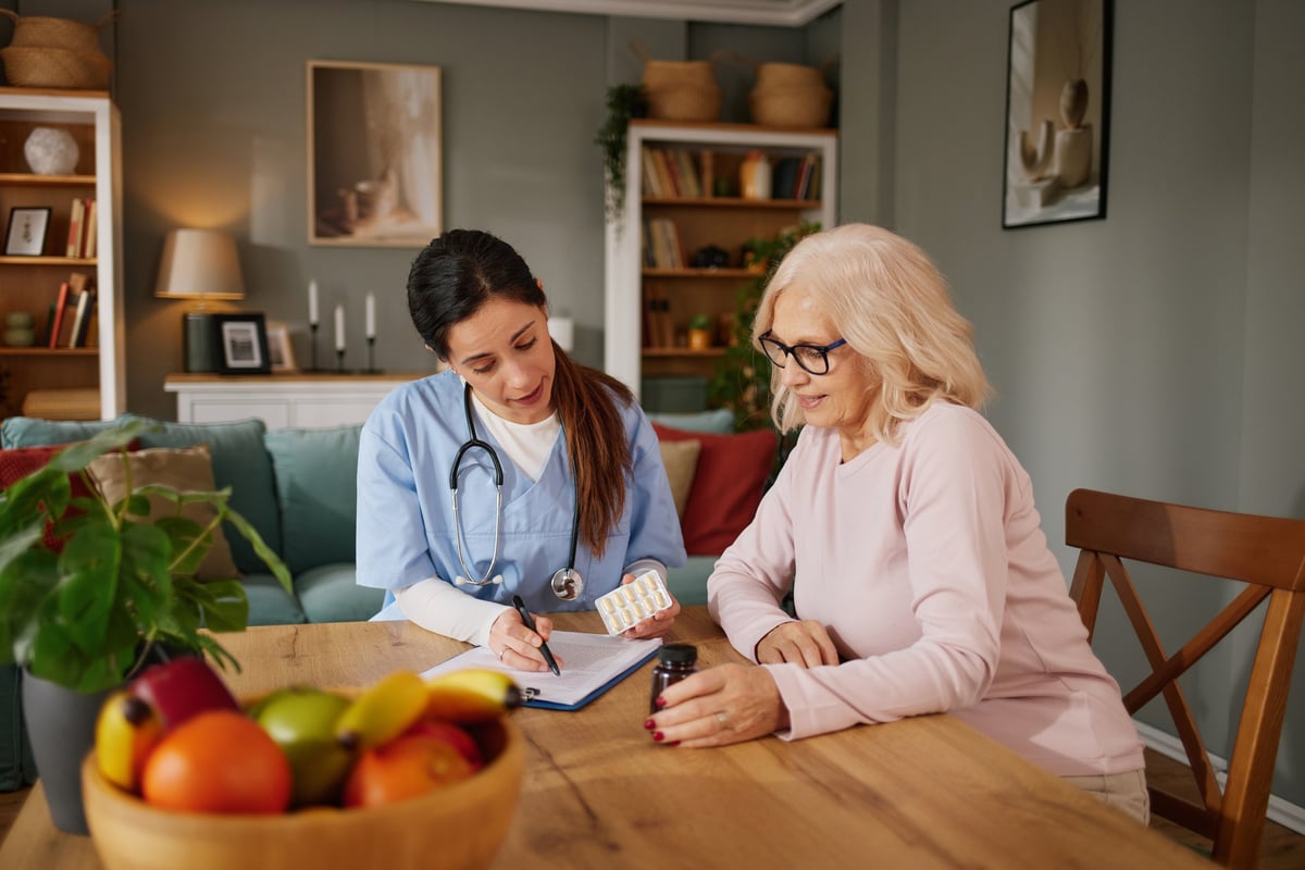 Nurse discussing medication with elderly patient during home visit