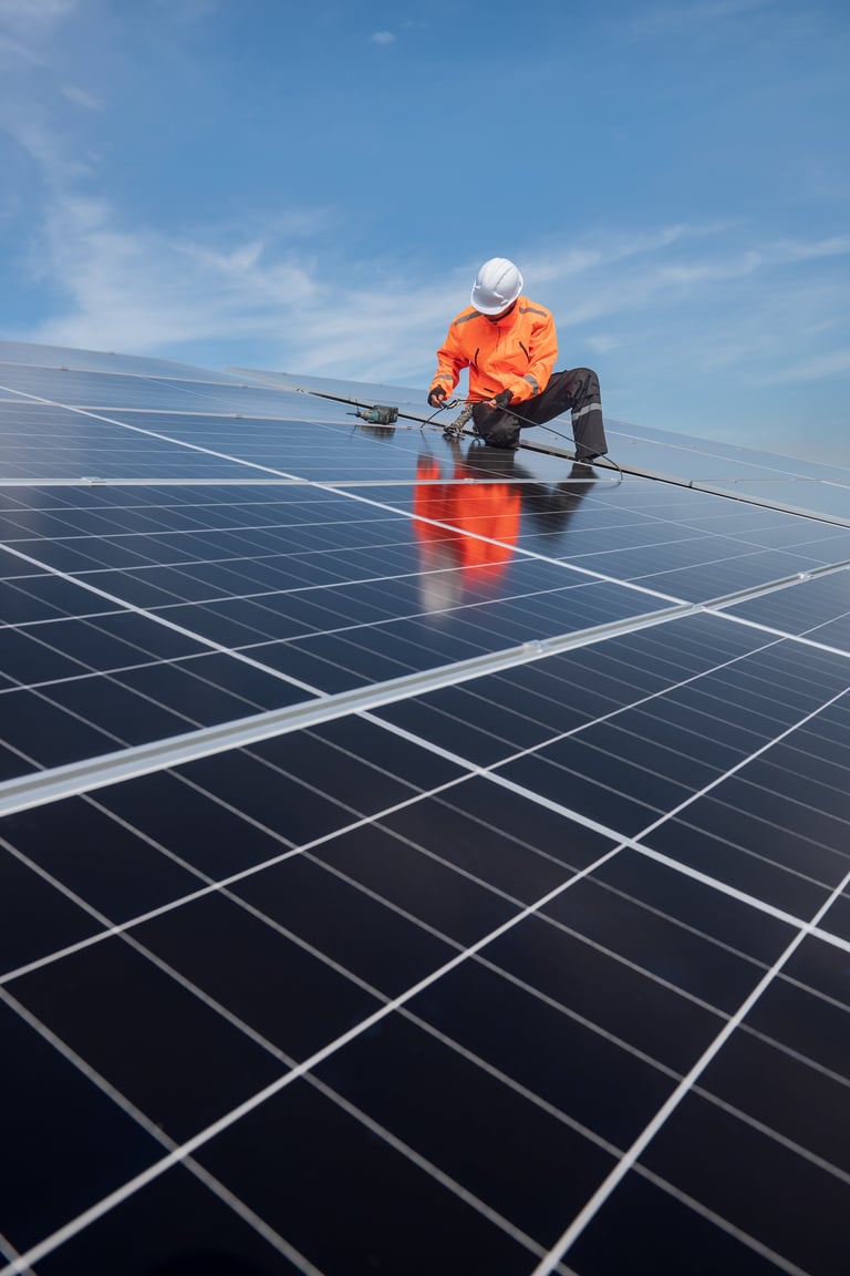 Technician installing solar panels on factory roof for green energy