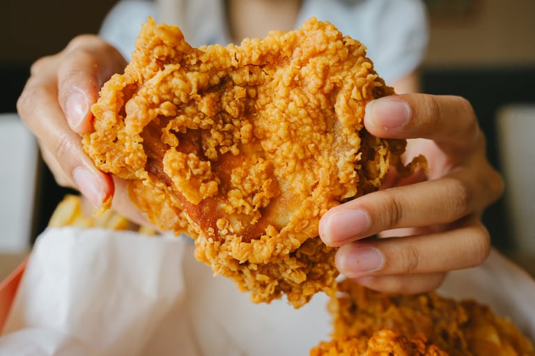 Crispy fried chicken held by hands showing golden crunchy texture