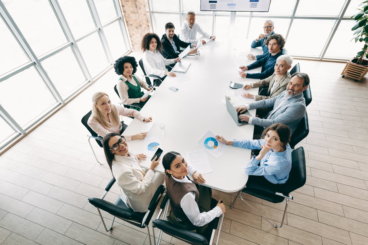 A diverse group of professionals engaged in a meeting around a large table, emphasizing teamwork, collaboration, and business development