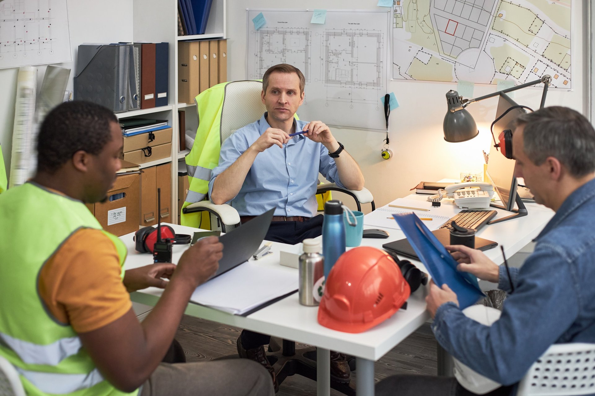 Engineers discussing construction plans and reviewing documents in office