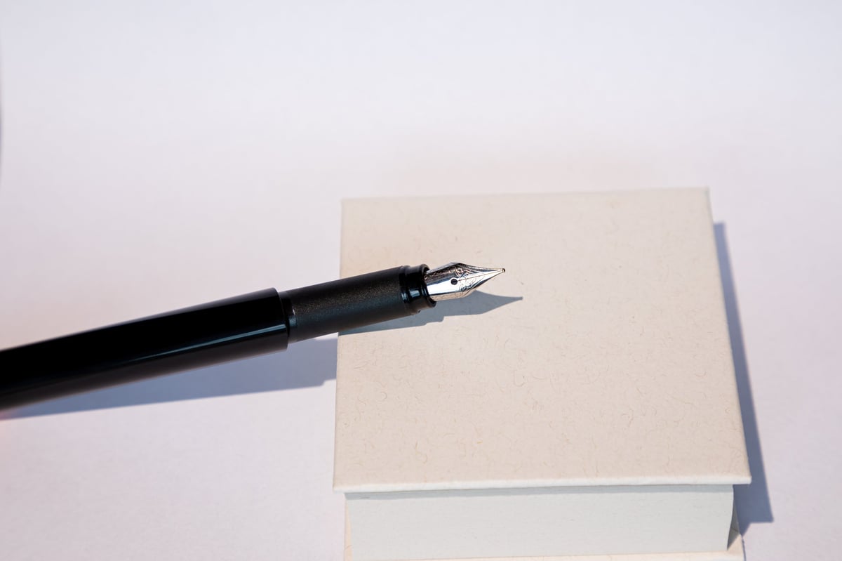 A fountain pen resting on white paper in soft natural light