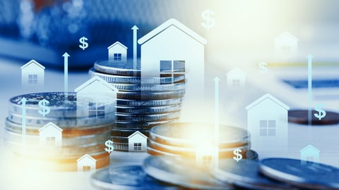 Stacks of coins with house icons showing investment growth in real estate