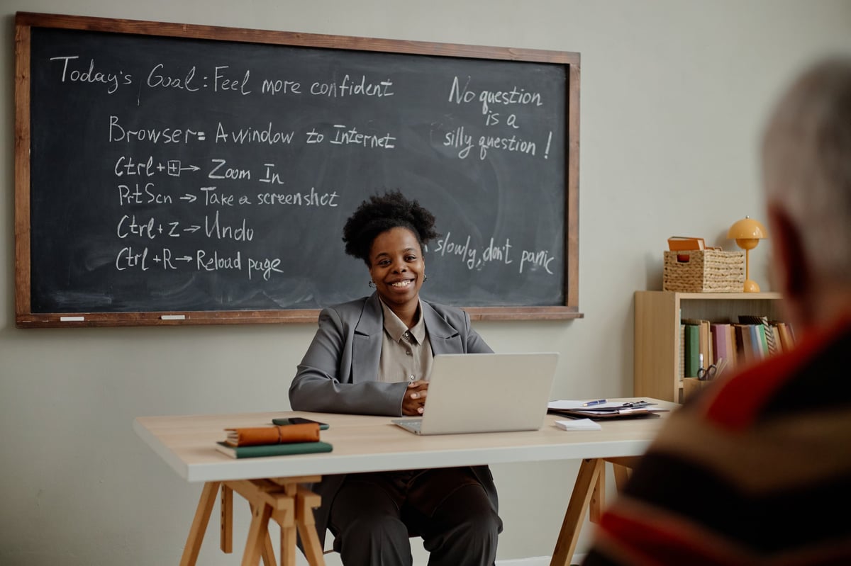 Smiling young adult Black woman teaching in classroom with laptop