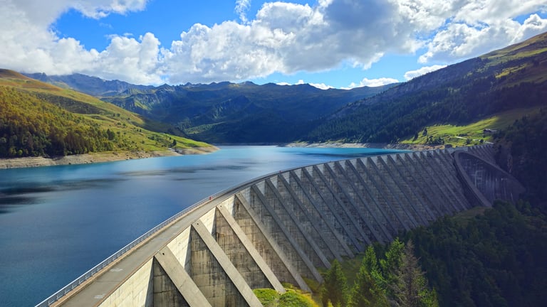 Roselend Dam holding reservoir water amidst French Alpine mountains, curved concrete dam in mountain landscape