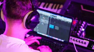Producer at desk with headphones, neon studio lighting