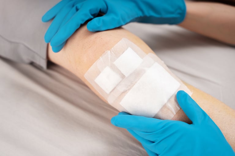Healthcare worker in gloves carefully adjusts adhesive dressing on patient's knee for wound care management
