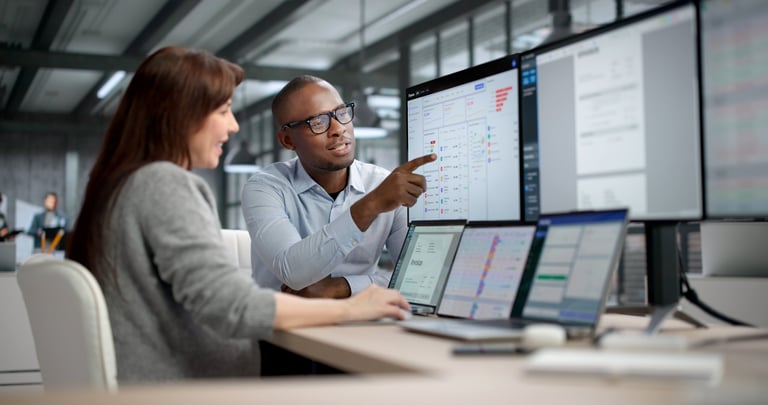 Two Professionals Analyzing Financial Reports And Tracking Data On Computer Screens