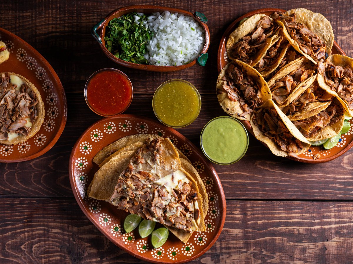 A variety of Mexican street tacos served with salsa and garnishes on a rustic wooden table