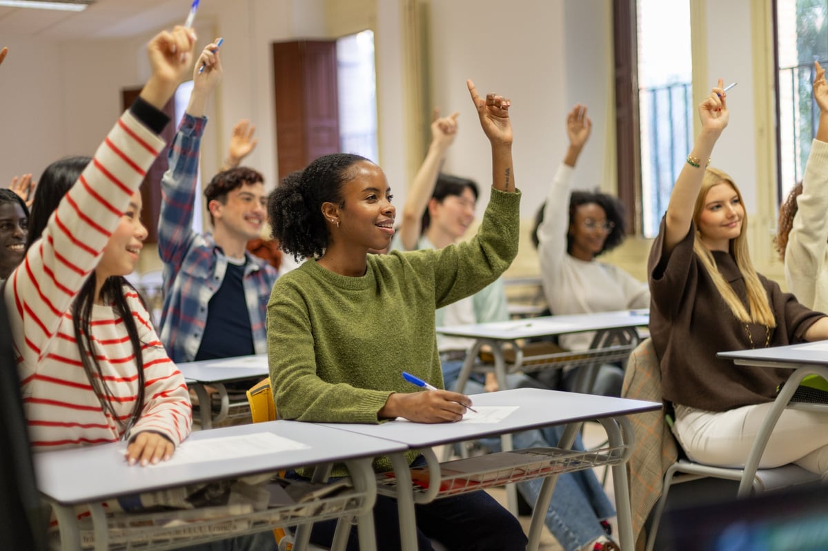 Black African American students actively participating in classroom, hands raised engaged in learning