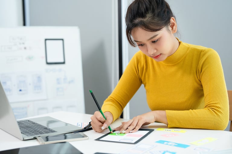 Mobile application design — UX designer sketching wireframes and interface layouts on paper at a creative workspace