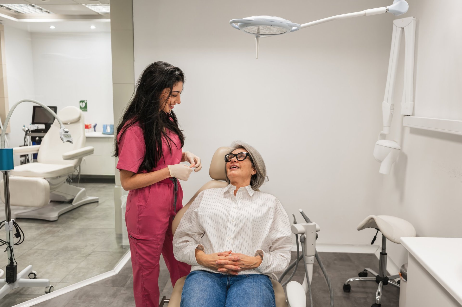 Female dentist gently talking with a smiling patient during a conservative dental checkup in a bright clinic