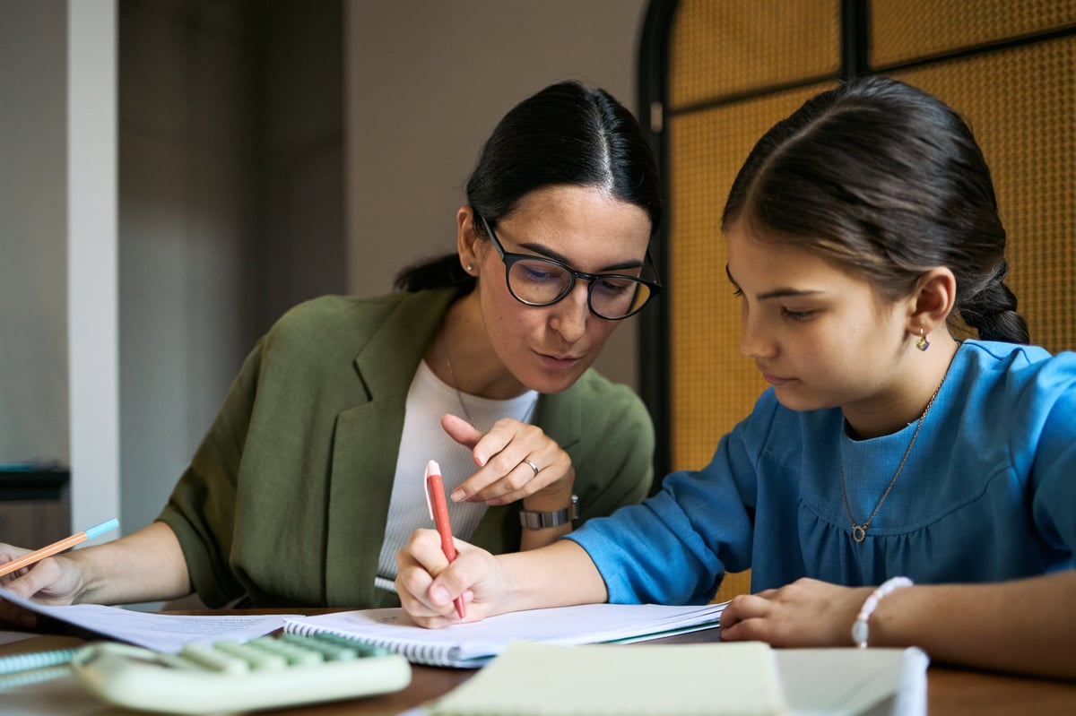 A Lighthouse teacher guiding a student through her schoolwork at her desk