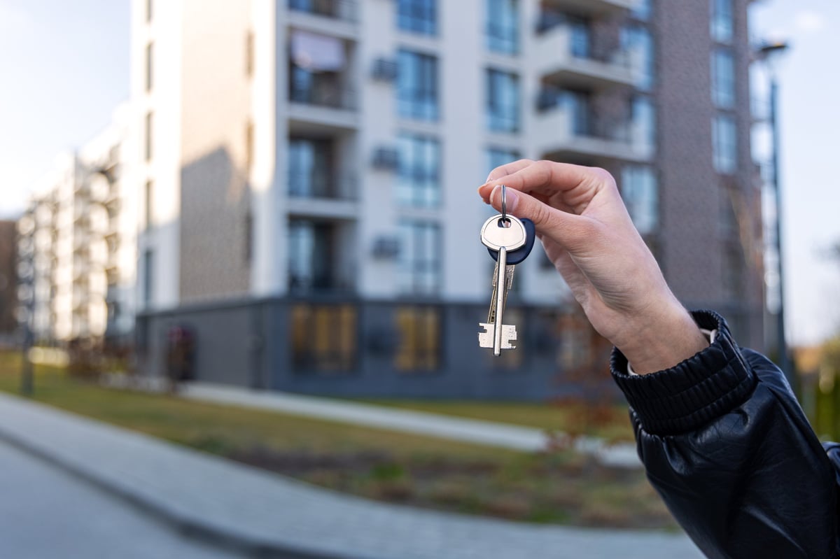 House keys held up in front of a modern residential neighborhood