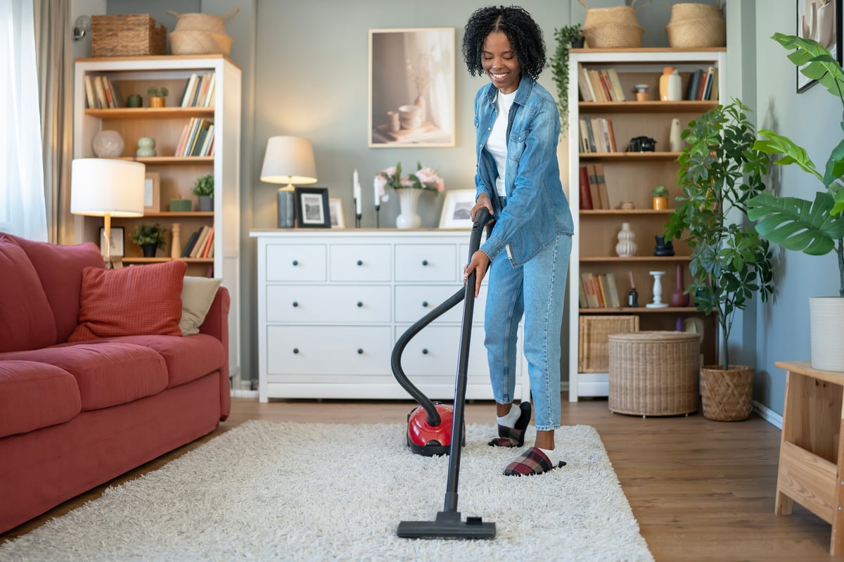 Woman deep-cleaning carpet with VORA vacuum — a cleaner, fresher home