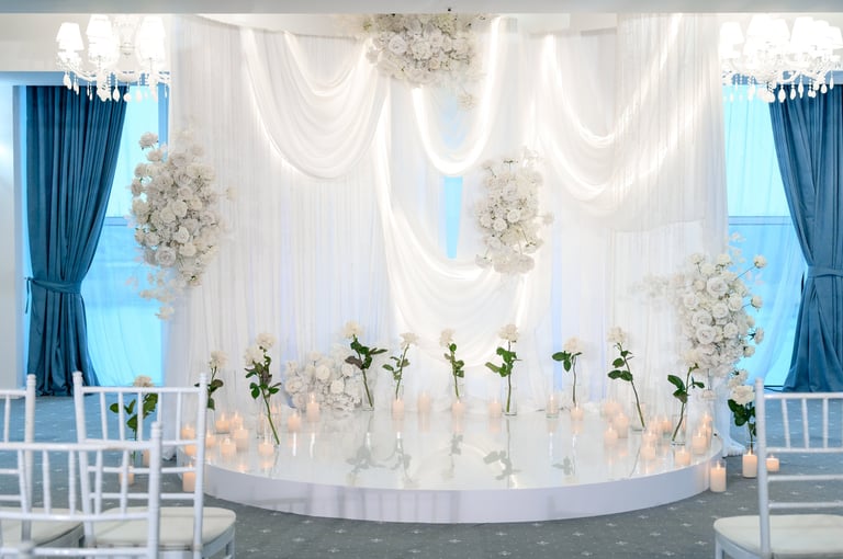 Beautifully arranged wedding ceremony backdrop with white flowers and draped fabric