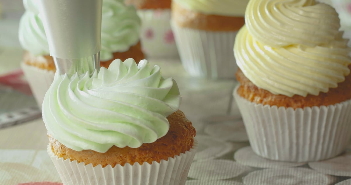 Baker piping frosting onto cupcakes in our kitchen