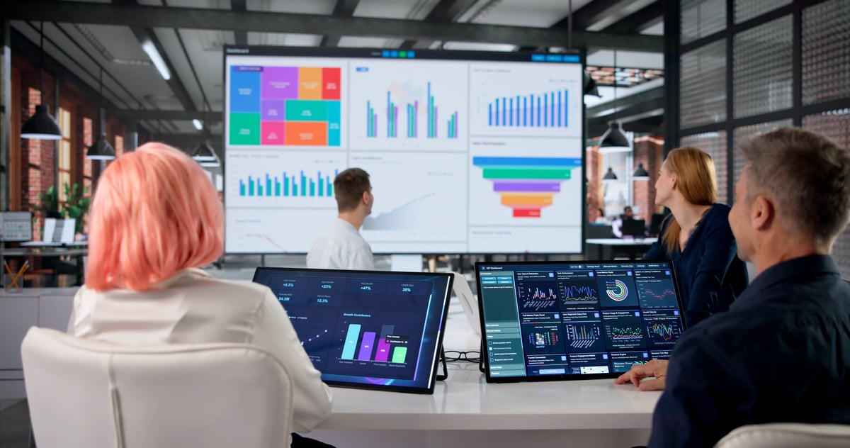 Financial analyst studies data dashboard during team meeting discussion on AI workflow and enterprise automation performance