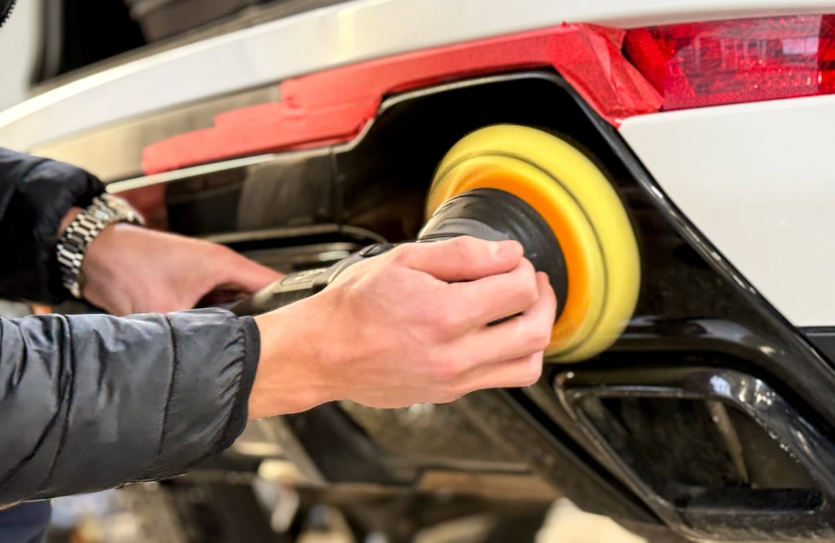 Detailer polishing a car body with an orbital polishing machine in an auto shop — KJAJ Details paint correction