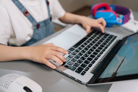 Child's hands typing on laptop keyboard — building typing skills at home