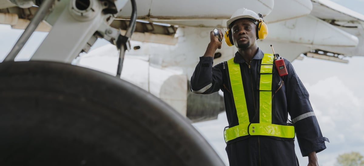 Mechanics inspect the engines of a large plane before takeoff at a summer airport
