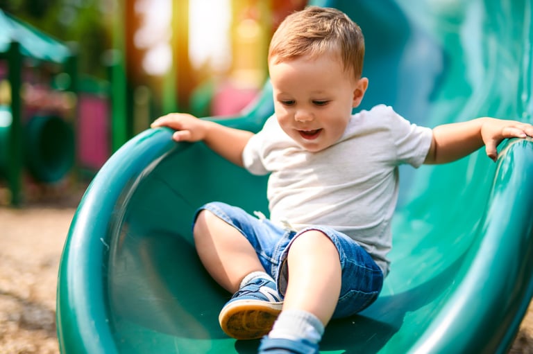 A baby playing on an outdoor playground in the kindergarten yard