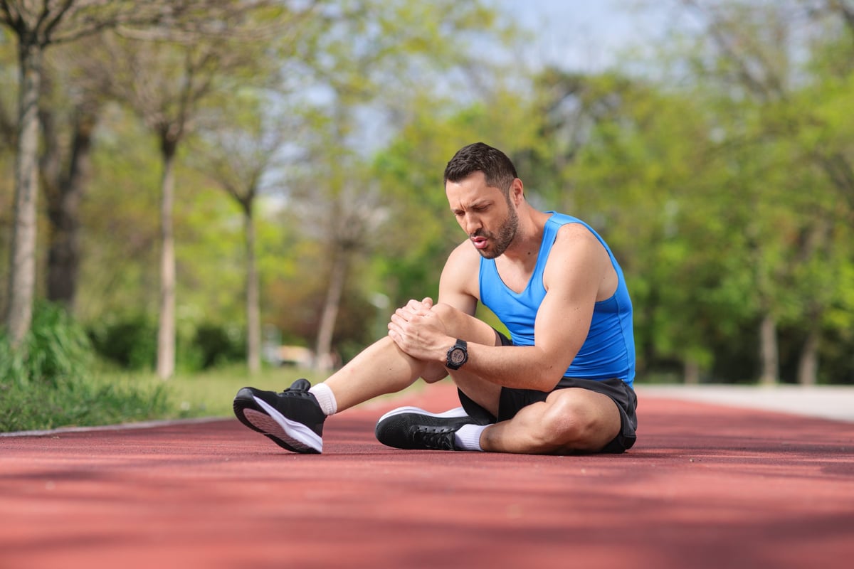 Deportista con dolor de rodilla en pista — lesión deportiva