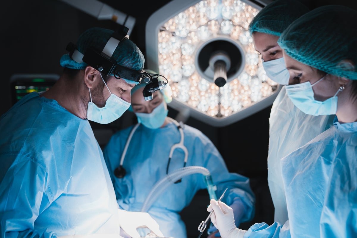 Equipo de cirujanos realizando procedimiento intervencionista vascular en quirófano moderno